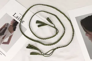 Macro view of vintage green braided belt with decorative tassel details on white