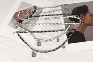 Detailed view of multilayer silver chain waist belt with woven leather and lock charms.