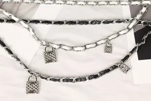 Detailed macro view of silver multi-layer woven metal waist chain with lock pendants.
