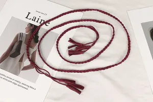 Detailed shot of a retro burgundy braided waist rope with tassels on fashion magazine