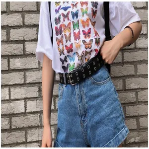 Close-up of a punk-style black double-grommet leather belt on denim shorts