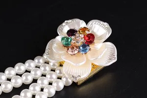 Close-up detail of four-row pearl belt featuring a colorful rhinestone flower buckle