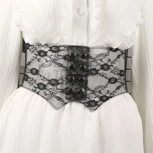 Close-up detail of a black floral lace elastic corset belt with snap buttons on a white ruffled dress