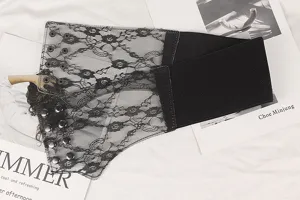 Detailed view of wide black lace elastic waist seal with decorative snap buttons