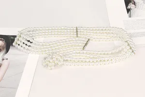 Detailed view of elegant four-row pearl belt with a sparkling rhinestone flower buckle