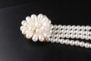 Close-up detail of a vintage four-strand pearl belt with a large flower buckle