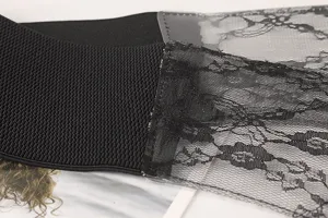 Macro view of black floral lace overlay on a wide elastic waist cincher belt for women
