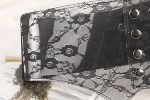 Macro view of black floral lace texture and metal snap buttons on wide corset belt