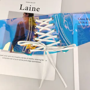 Close-up of holographic PVC lace-up corset belt with white laces on a magazine background.