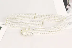 Close-up detail of elegant four-row pearl waist belt with a vintage rhinestone flower buckle