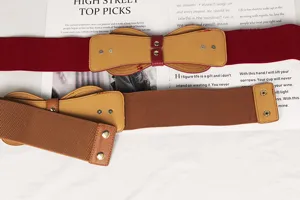 Détail de la ceinture élastique large avec un nœud élégant et des boutons-pression métalliques.