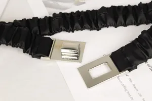 Detailansicht eines schwarzen plissierten elastischen Gürtels mit silberner Schnalle