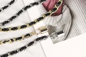 Detail of metallic chain waist belt with black leather and small padlock charm