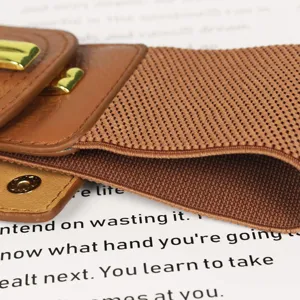 Gros plan sur une ceinture élastique marron pour femme avec une boucle dorée chic