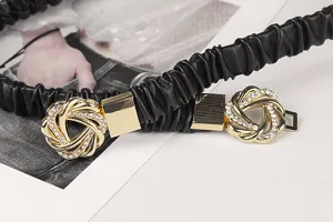 Nahaufnahme eines schwarzen, elastischen Faltengürtels mit goldener, strassbesetzter Schnalle