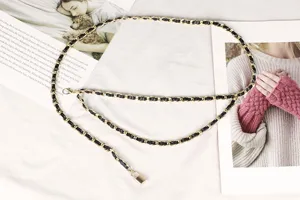 Detailed view of dual-layer gold metal chain belt with black leather weave