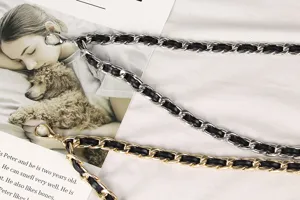 Close-up of gold and silver metal waist chains interwoven with black leather straps