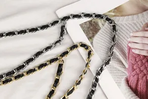 Detail view of gold and silver metal chain belts interwoven with black leather