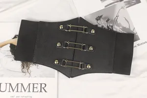 Détail de la large ceinture élastique noire avec boucles métalliques dorées triples.