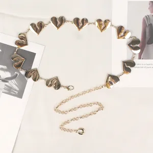 Close-up van gouden hartvormige metalen taailleketting accessoire op een witte achtergrond
