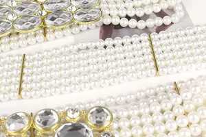 Detailed view of white pearl rows and sparkling rhinestones on an elastic waist belt.