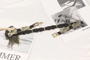 Close-up view of thin black elastic belt featuring gold metal buckle and textured plates