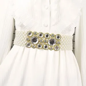 Close-up detail of a wide elastic pearl waist belt with sparkling rhinestone centerpiece