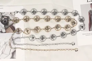 Dettaglio di cinture a catena in metallo color oro e argento con ciondoli a fungo.