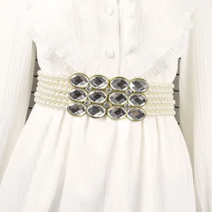 Macro view of elegant pearl elastic waist belt with sparkling rhinestone buckle.