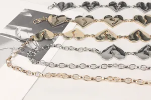 Close-up van stijlvolle hartvormige metalen taillekettingen in goud en zilver