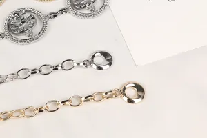Dettaglio di catene da vita in metallo oro e argento con pendenti a forma di globo.