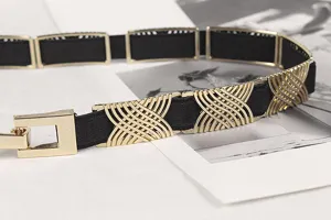 Close-up detail of the gold interlocking metal pattern on a slim black elastic waist belt