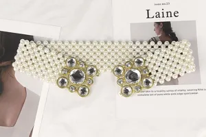 Close-up of elegant white pearl beaded elastic belt featuring ornate rhinestone gold buckles
