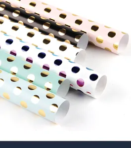 Detail of gold polka dot wrapping paper rolls in elegant pastel colors.