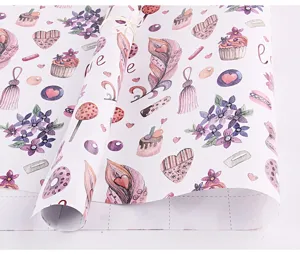 Gros plan montrant le motif de cupcake et de fleurs violettes sur du papier cadeau épais
