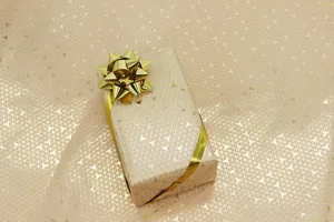 Détail d'un papier cadeau or rose avec motif triangles dorés et nœud scintillant.