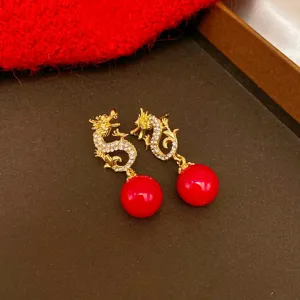 Detailaufnahme festlicher goldener Drachenohrringe mit roten Perlen und glitzernden Steinen