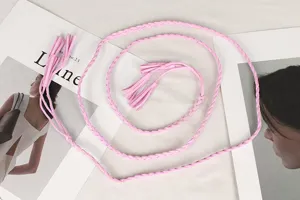 Detail view of a pink braided waist rope belt with tassels for vintage dress decoration