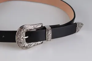 Primo piano di una cintura western vintage nera con fibbia in argento floreale incisa
