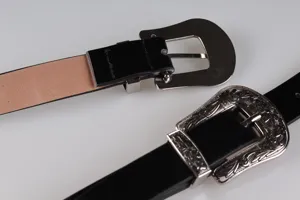 Dettaglio ravvicinato della cintura vintage nera con fibbia western incisa a fiori argentati