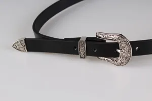 Primo piano di una cintura nera vintage Y2K con fibbia argentata decorata a fiori.