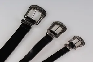 Dettaglio delle fibbie in argento inciso su cinture nere vintage in stile Y2K