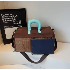 Large brown travel bag with blue handles shown next to a tablet for size reference.