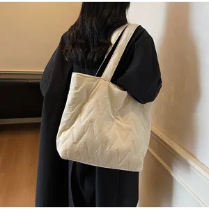 Vista trasera de modelo con un bolso tote acolchado crema de gran capacidad