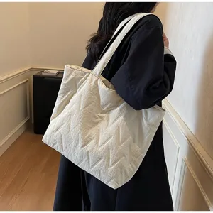 Primer plano de un bolso tote acolchado blanco de gran capacidad con textura de chevrón en modelo.