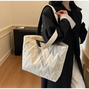 Vista detallada de un bolso tote de lona acolchada blanca llevado por una modelo