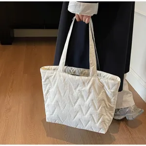 Detalle del relieve con patrón en V de este bolso tote acolchado grande de color blanco roto