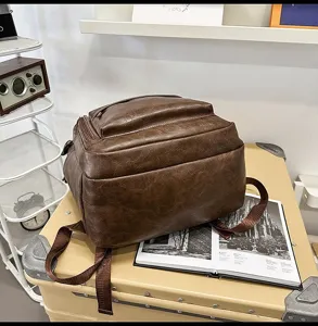 Primer plano de una mochila vintage de cuero marrón sobre una maleta de estilo retro