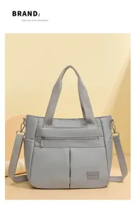 Nahaufnahme der grauen Schultertasche aus Nylon mit Gurtbandgriffen und Markenlabel
