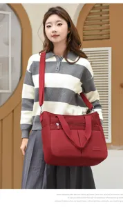 Modische burgunderrote Nylonschultertasche mit großer Kapazität, von Model im Freien getragen